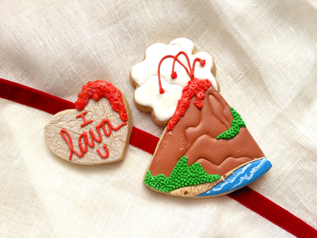 Pair of Valentine cookies featuring a heart and volcano and the words 